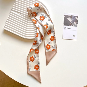 Detail shot of a satin floral scarf featuring orange flower patterns and champagne tips