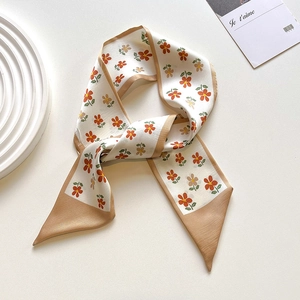 Detail of floral silk scarf with warm orange flowers and champagne gold border