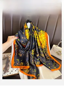 Detail of silk scarf showing black satin texture with yellow flowers and orange borders