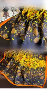Detail of floral silk scarf showing vibrant orange hem and smooth printed fabric texture