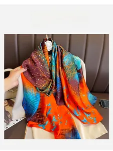 Detail of silk-like scarf featuring orange and blue branch patterns and bird prints