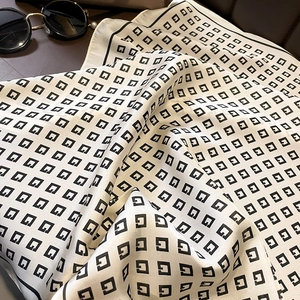 Detail of silk-like square scarf featuring geometric G-pattern on cream background