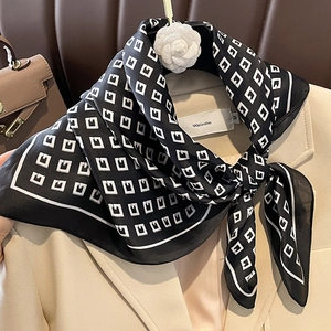 Macro shot of silk square scarf with white letter G pattern on beige blazer lapel