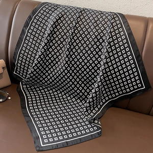 Close-up of a black and white geometric pattern scarf on a leather sofa with accessories