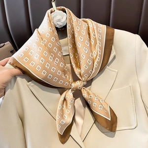 Detail of silk square scarf with geometric pattern styled on a beige blazer collar