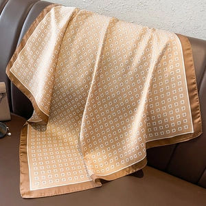 Close-up of geometric pattern silk scarf draped over a brown leather sofa