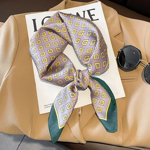 Lilac silk scarf with geometric G patterns and green edges on a fashion magazine