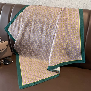 Detail of silk scarf with geometric patterns draped on a leather sofa with accessories