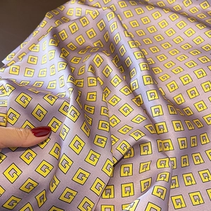 Detail of purple satin scarf featuring yellow geometric G-pattern and silky texture