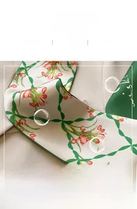 Detail of green floral patterned silk scarf showing fine twill fabric and delicate stitching