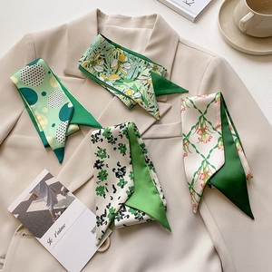Detail of four green French style silk twilly scarves with floral patterns on a blazer