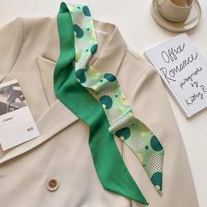 Polished green silk scarf with geometric dot patterns on a beige blazer background
