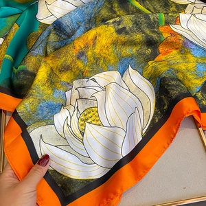 Macro detail of silky floral scarf showing soft texture and vibrant lotus print
