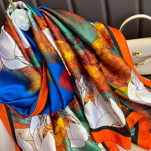 Detailed close-up of artistic silk scarf with white lotus patterns and orange trim finish