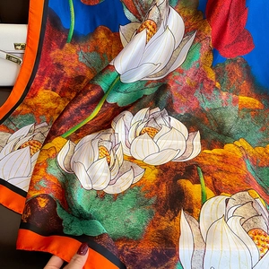 Detail of silk scarf with vibrant lotus floral pattern and orange border finish
