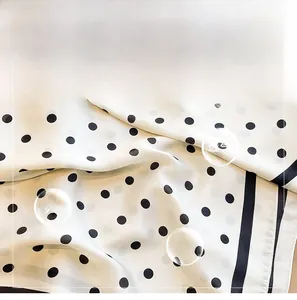 Vue détaillée d'une écharpe en soie blanche à pois noirs et texture sergé fin