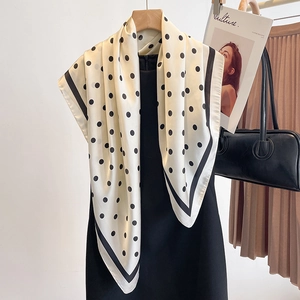 Élégant foulard en soie à pois noir et blanc, drapé sur une robe pour un look chic