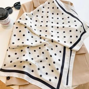 Élégant carré de soie à pois sur blazer beige avec lunettes de soleil et café
