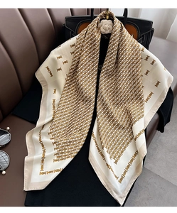 Detailed view of luxury silk scarf with monogram print draped on black clothing
