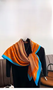 Macro detail of silk scarf featuring monogram print and contrast blue hem on a mannequin