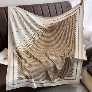 Detail of elegant monogram patterned silk scarf draped on a brown leather texture