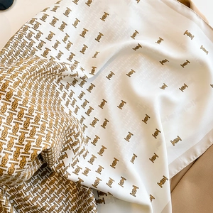 Detailed view of white silk scarf showing TB monogram pattern and satin texture