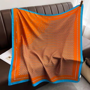 Detailed view of large square silk scarf featuring orange and blue contrast H-pattern