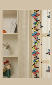 Detailed close-up of butterfly embroidery on semi-transparent lace curtains with floral patterns