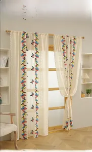 Detail of sheer butterfly embroidered curtains with lace edges in a warm home setting