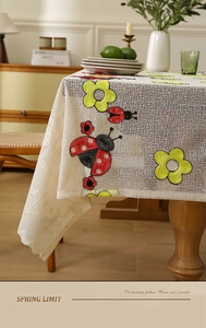 Detailed embroidery of yellow flowers and ladybugs on white lace mesh tablecloth