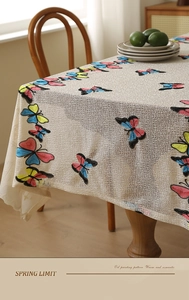 Detailed close-up of butterfly embroidery on woven cream tablecloth with a romantic aesthetic