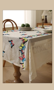 Detail of colorful butterfly embroidery on cream lace tablecloth with mesh texture
