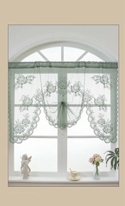 Close-up of sage green lace cafe curtain with delicate rose embroidery and wavy edges