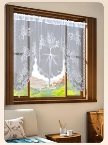 Detail of white lace cafe curtain featuring intricate floral embroidery and scalloped edges