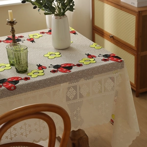 Grey linen textured tablecloth with embroidered ladybugs and white lace borders