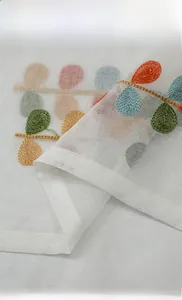 Detail of multi-color leaf embroidery on white linen textured sheer cafe curtain