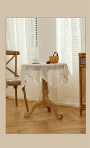 Close-up of off-white lace round tablecloth with intricate floral hollow crochet patterns