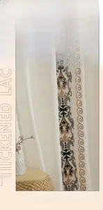 Dettaglio del ricamo in pizzo ispessito su tende in lino beige per camera da letto