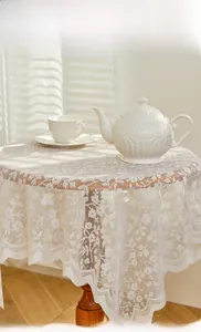 Detailed view of white floral lace tablecloth with intricate hollow embroidery texture