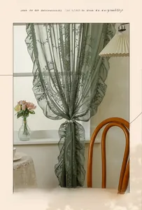 Detail of dark green lace curtain with floral patterns and pearl tieback for window decor
