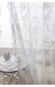 Detailed view of white floral lace curtain with romantic ruffled edges and rose embroidery