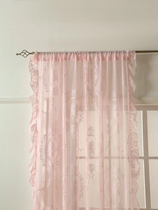 Detail of light pink vintage lace curtain with floral embroidery and ruffled edges