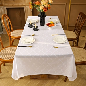 White rectangular tablecloth with embossed clover patterns on a wooden dining table