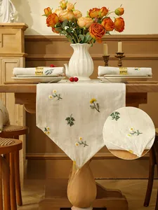 Close-up of linen table runner featuring wheat embroidery and white tassel fringe details