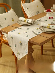 Close-up of rustic linen table runner with embroidery and woven fringe details