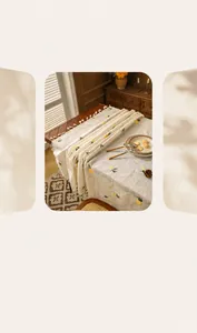 Close-up of beige linen tablecloth with yellow botanical prints and tassel edge detail