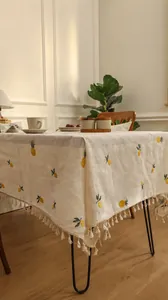 Close-up of beige linen tablecloth with pineapple embroidery and decorative tassel edges