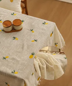 Close-up of linen tablecloth with yellow pineapple embroidery and white tassel fringe