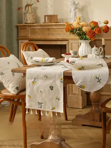 Close-up of floral embroidery on linen table runner with elegant white fringe details
