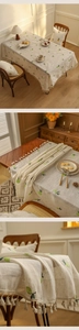 Close-up of beige linen tablecloth featuring green pineapple embroidery and tassel edges